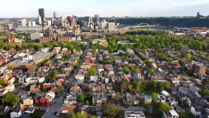 Aerial view of downtown Pittsburgh, Pennsylvania with dense, low-rise housing in foreground.
